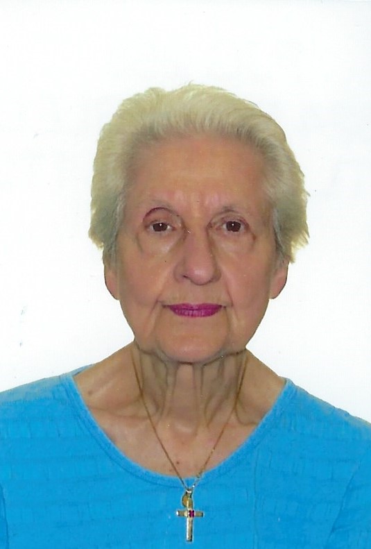 Portrait de Lise, femme aux cheveux courts gris portant un haut bleu et un pendentif en forme de croix